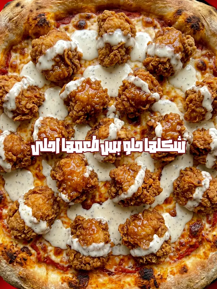 Close up food photography: pizza topped with crispy chicken bites and ranch drizzle